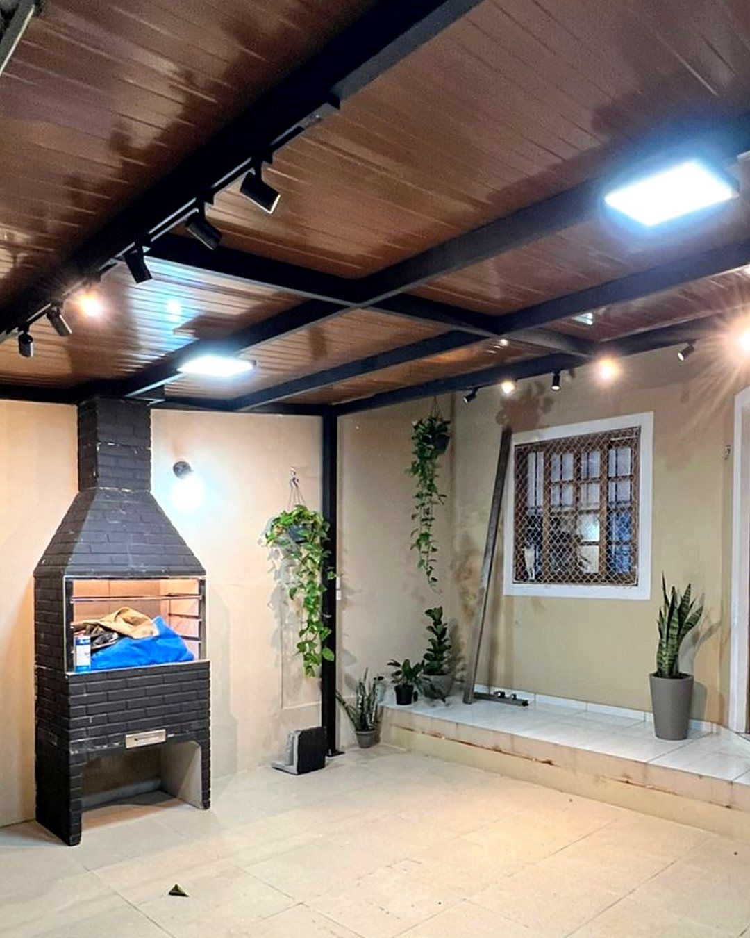 Área gourmet coberta com trilho de spots e painéis de LED acesos