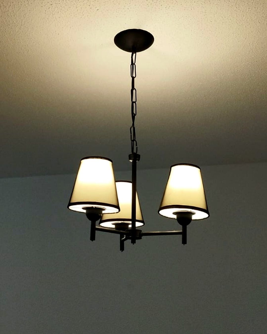 Lustre de três cúpulas aceso no teto